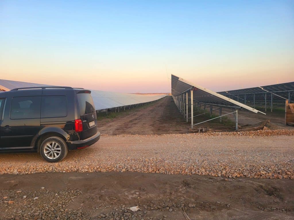 Solar power farm with solar panels and vehicle in the foreground.