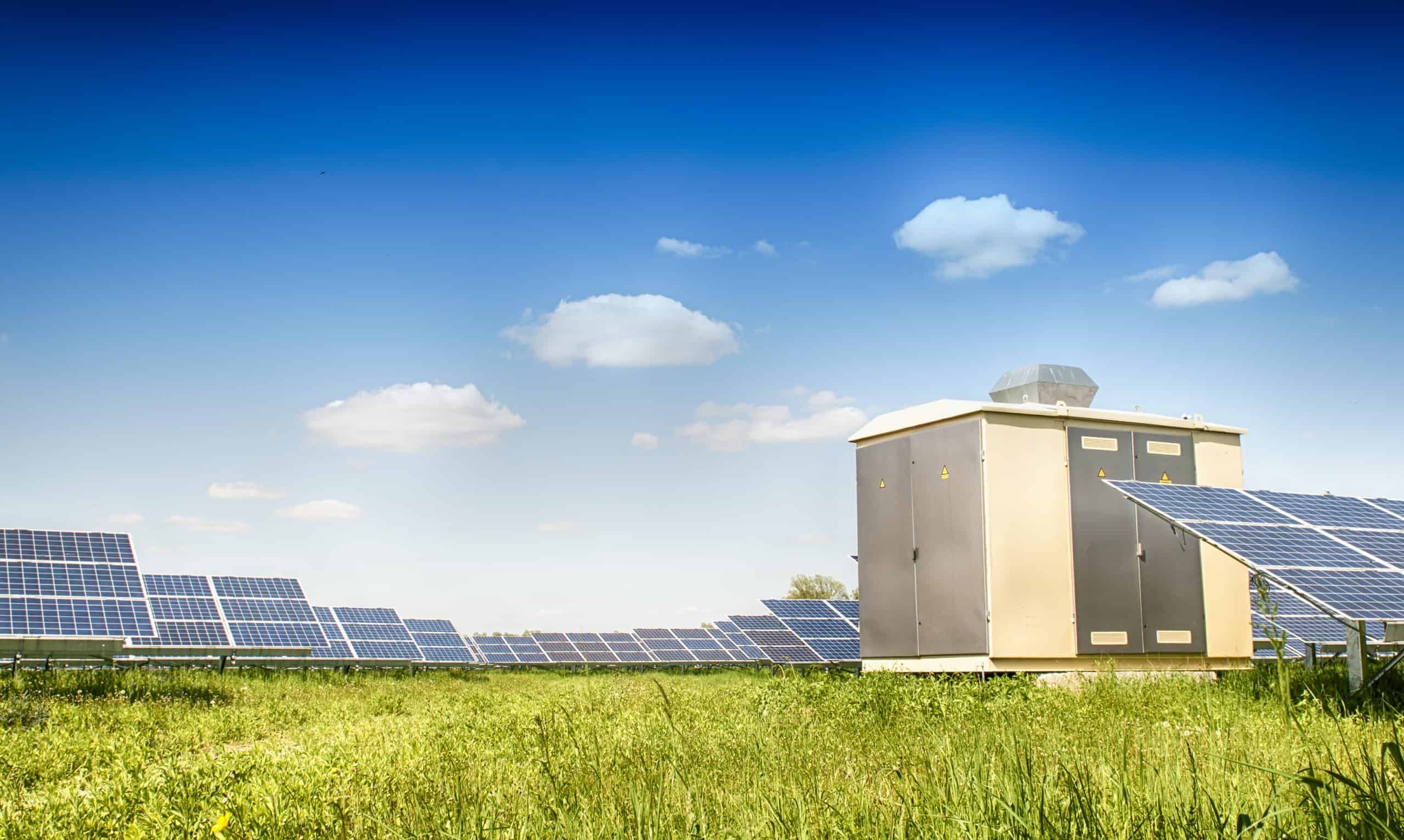 Solar energy system with battery storage and solar panels in a green field.