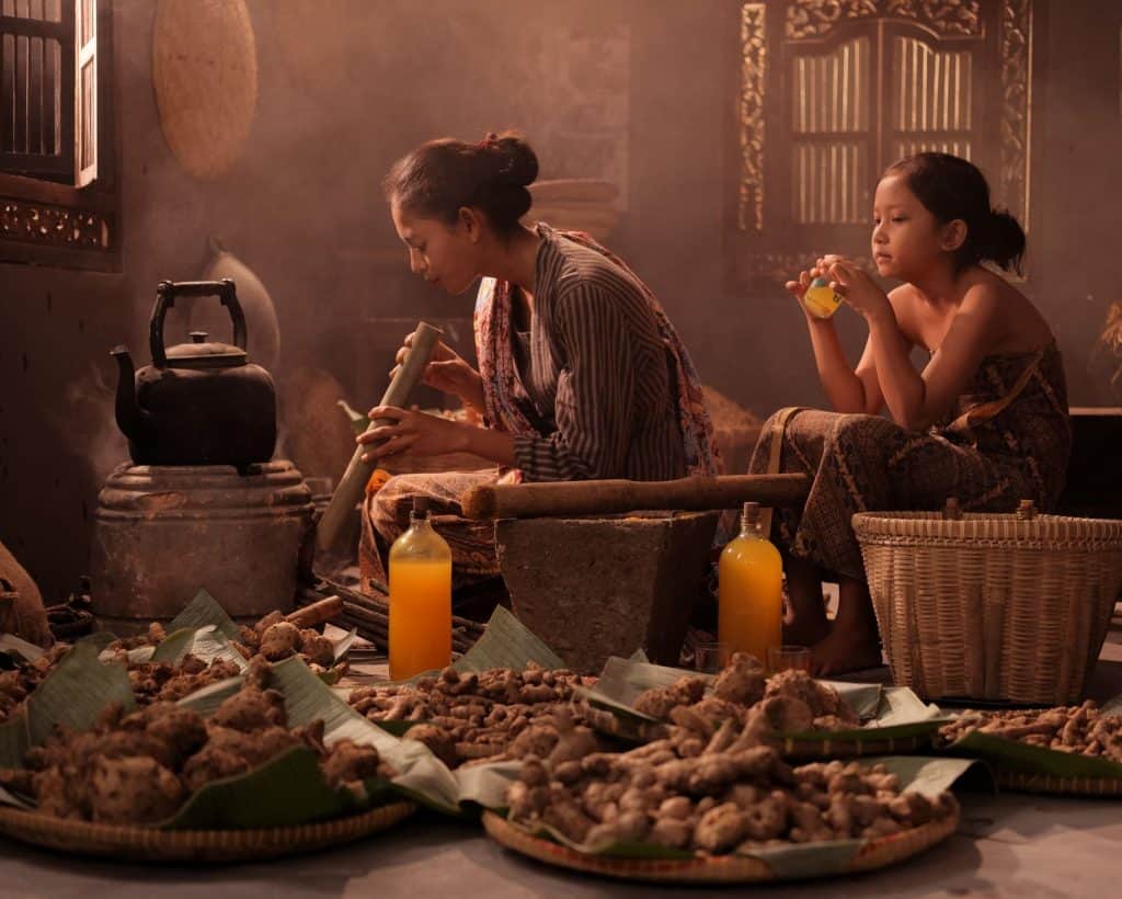 Mother and daughter preparing traditional Jamu in an Indonesian home setting.