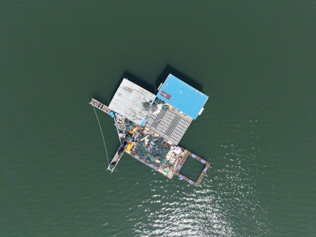 Aerial shot of a floating fishing platform with equipment in calm waters, ideal for marine concepts.