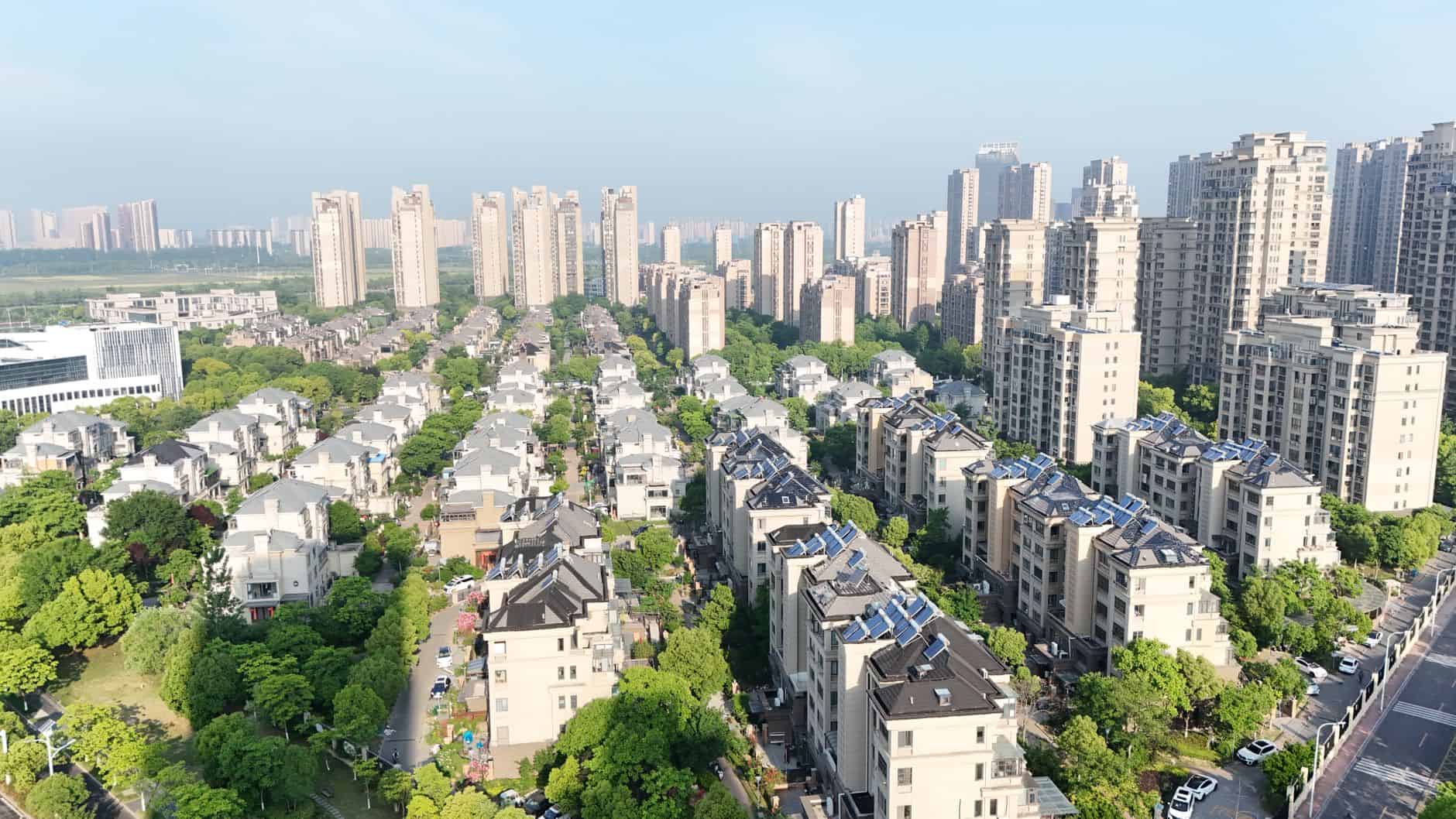 Aerial view of a city with residential buildings and green trees.