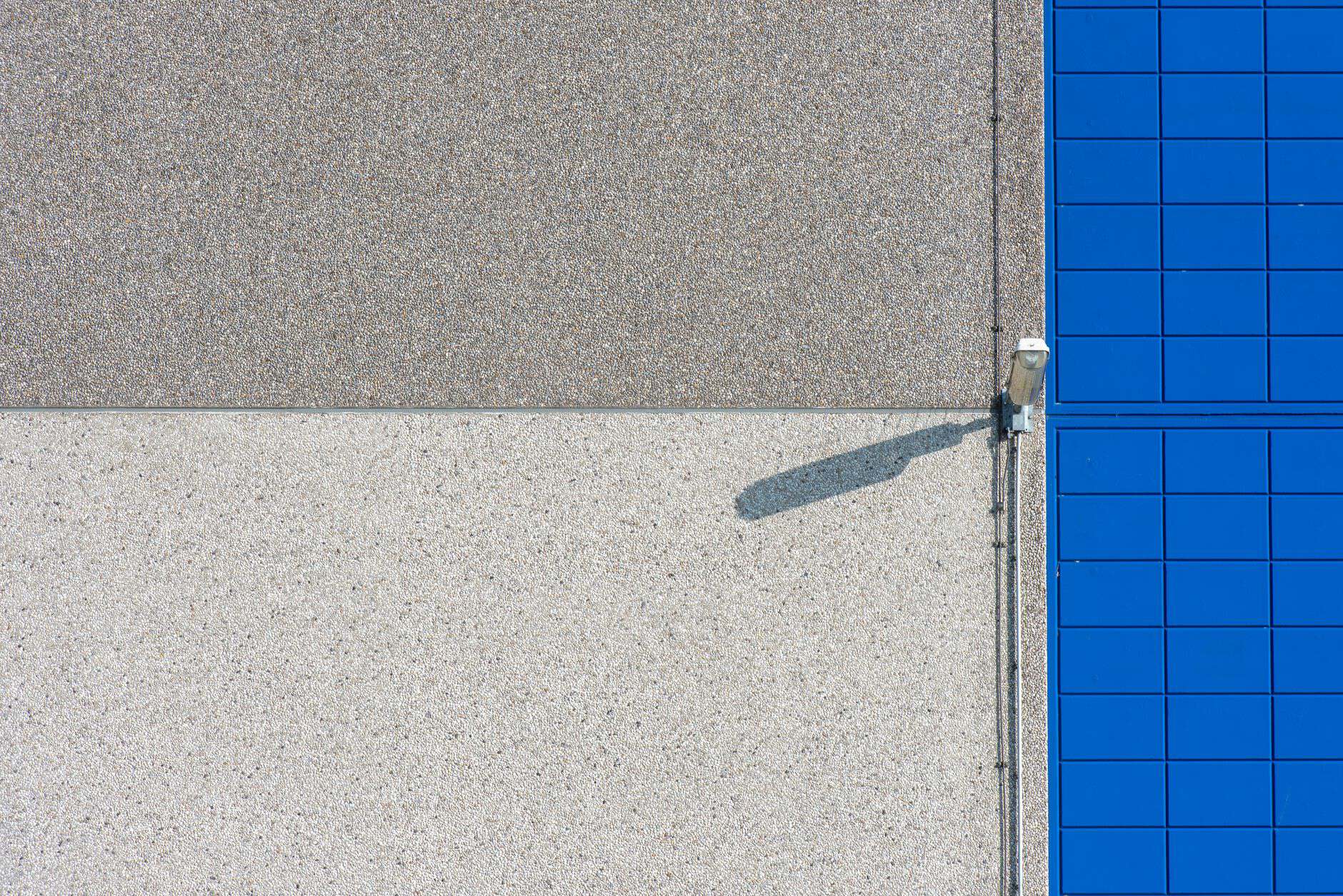 A modern building facade with solar panels and a security light, showcasing clean lines and textures.