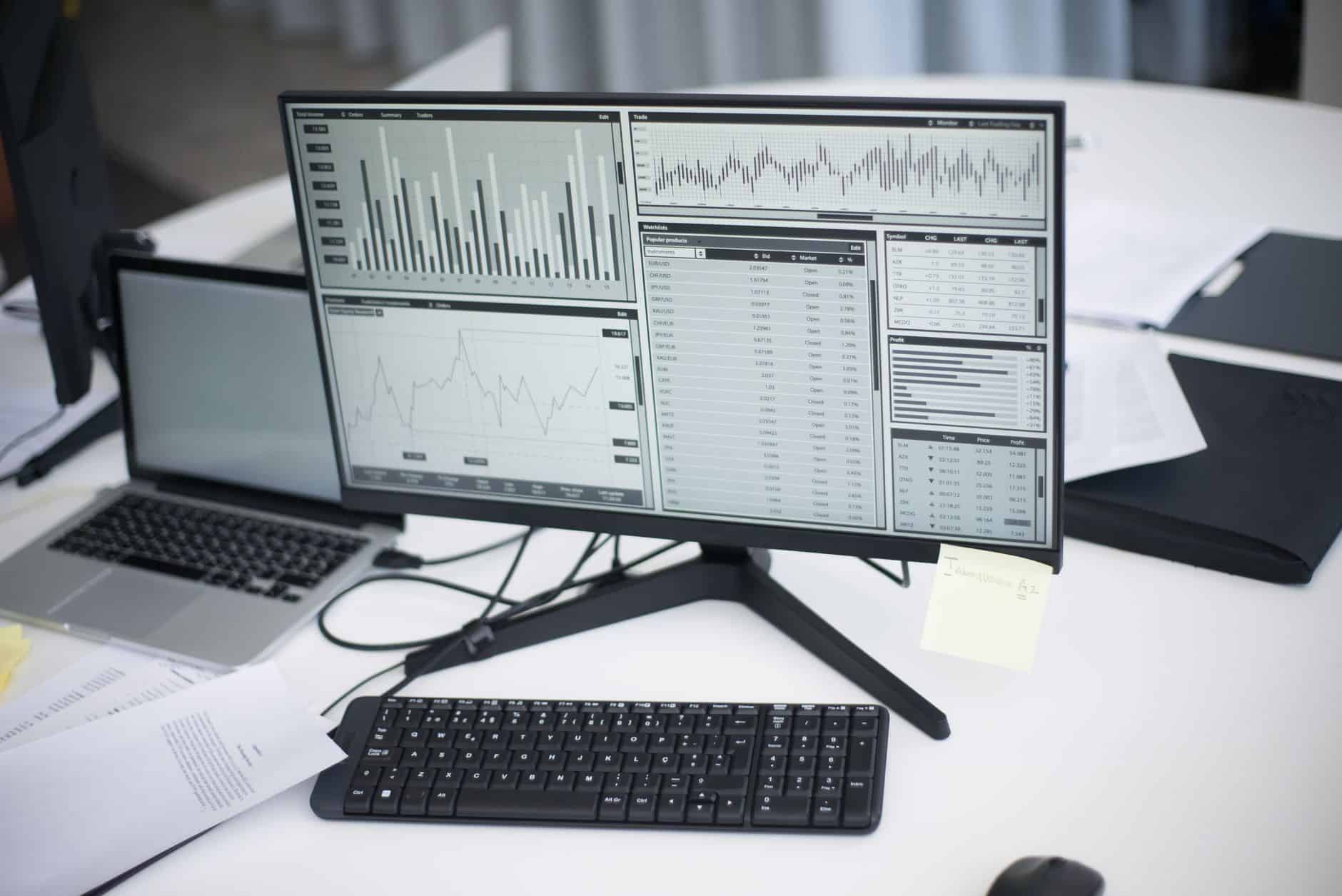A professional workspace featuring computers and analytical graphs on a monitor, symbolizing modern business environment