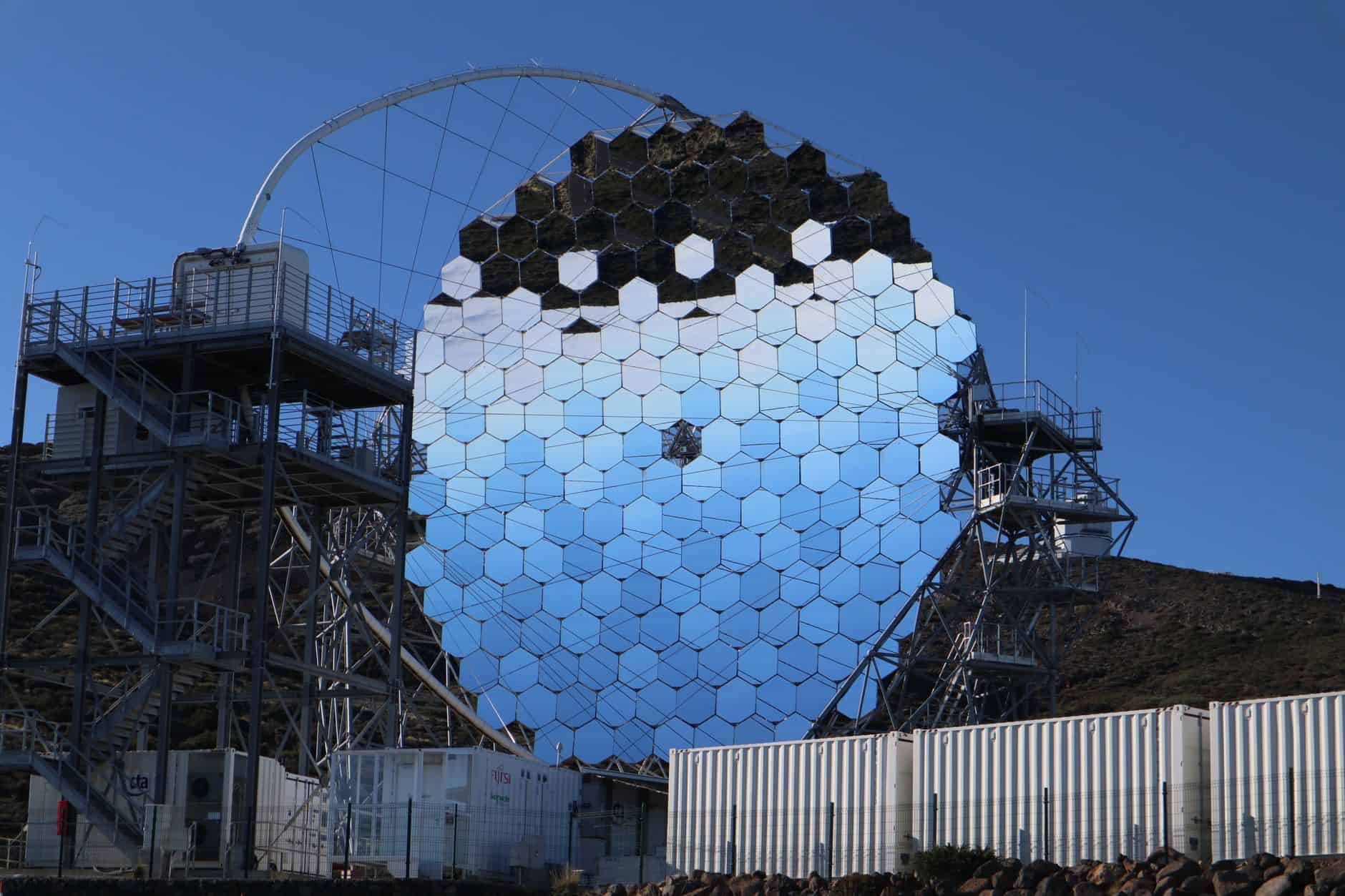 Futuristic reflective structure with hexagonal mirrors under a clear blue sky. Modern design.