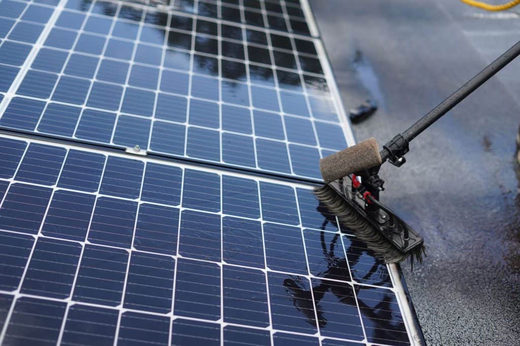 Cleaning solar panels with a water brush for optimal energy efficiency.