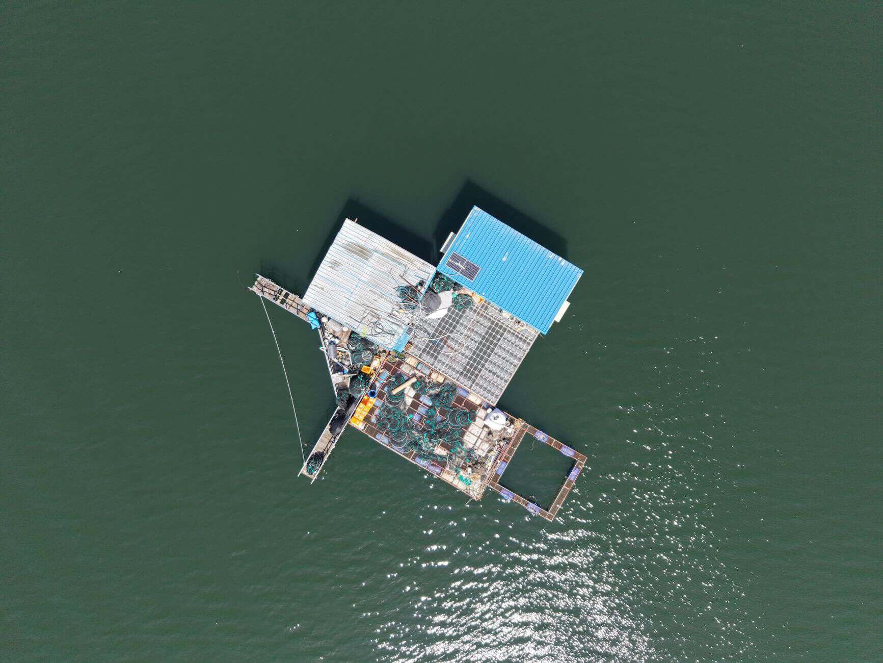 Aerial view of a solar-powered floating platform on water with solar panels and structures.