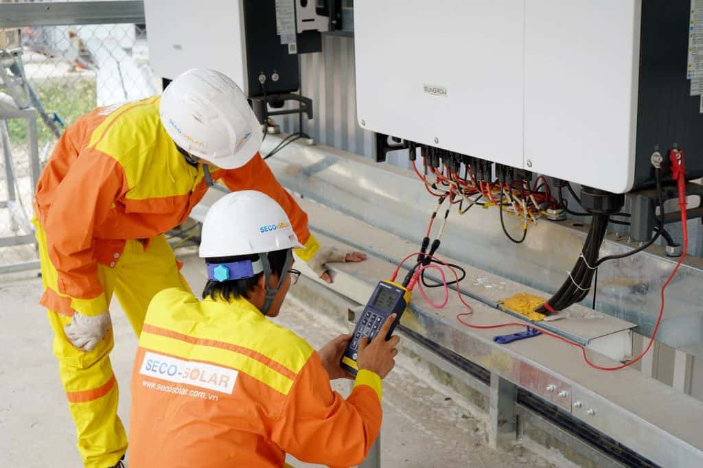 Technicians inspecting solar power system installation at a solar energy site.